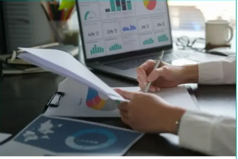 Hands reviewing a printed report beside a laptop