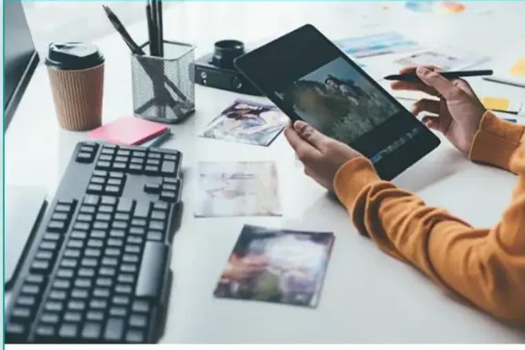 Someone reviewing photographs on a tablet at a desk